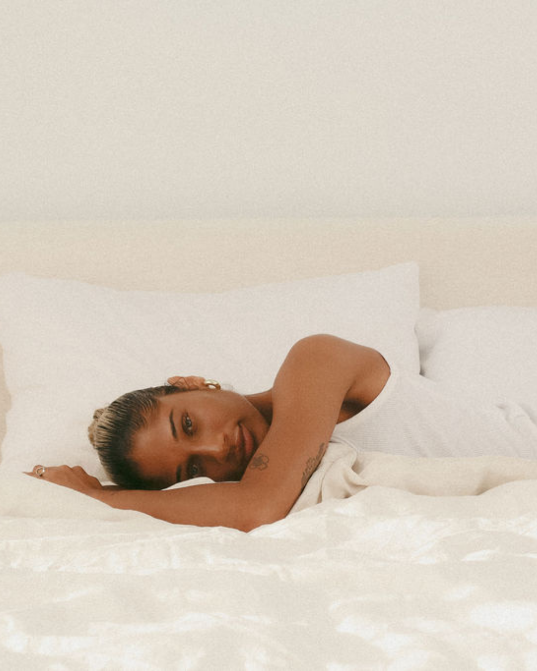 Woman lying in bed looking tired, representing signs of nervous system stress and poor sleep.